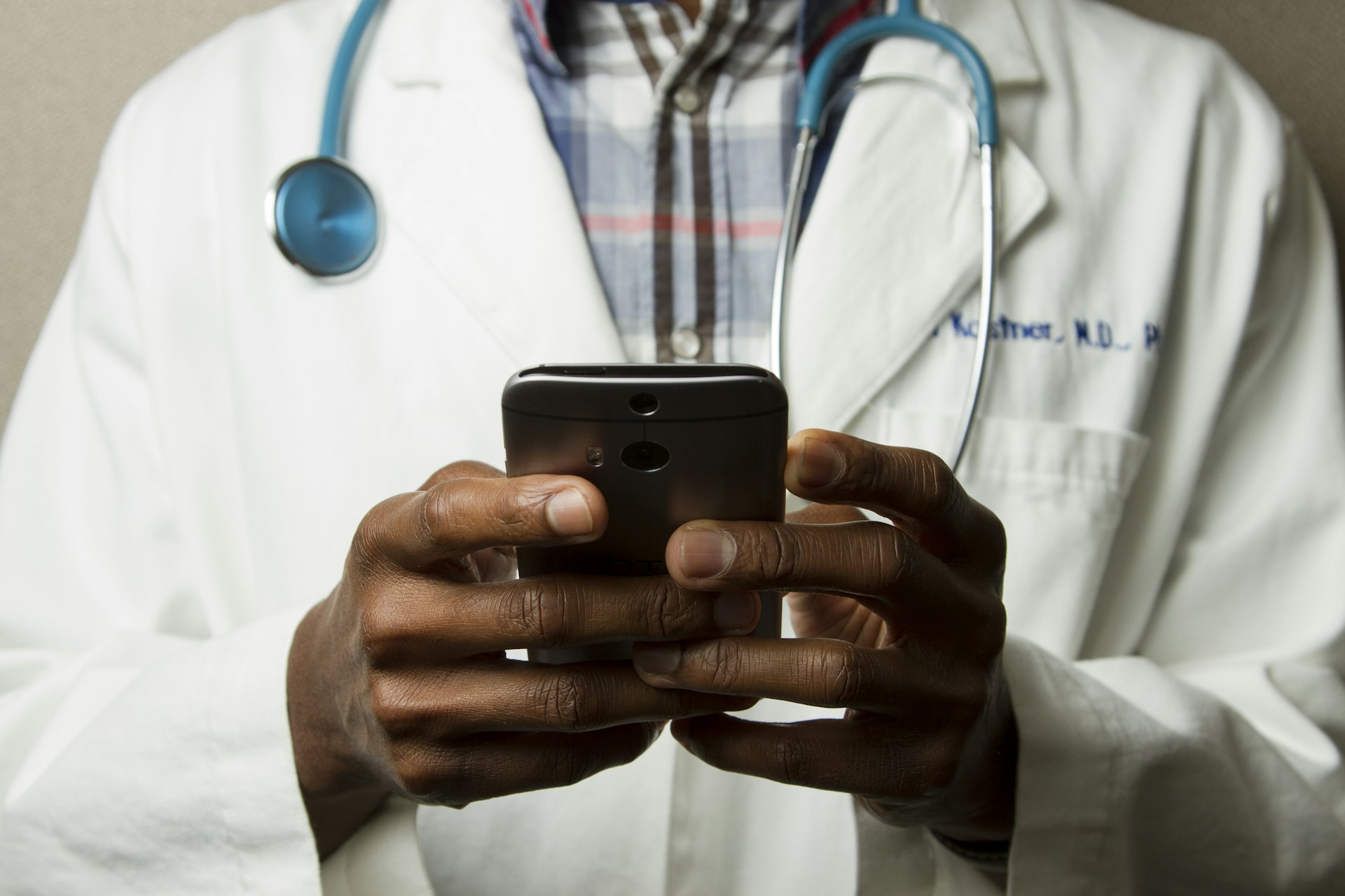 Medical professional with stethoscope using smartphone