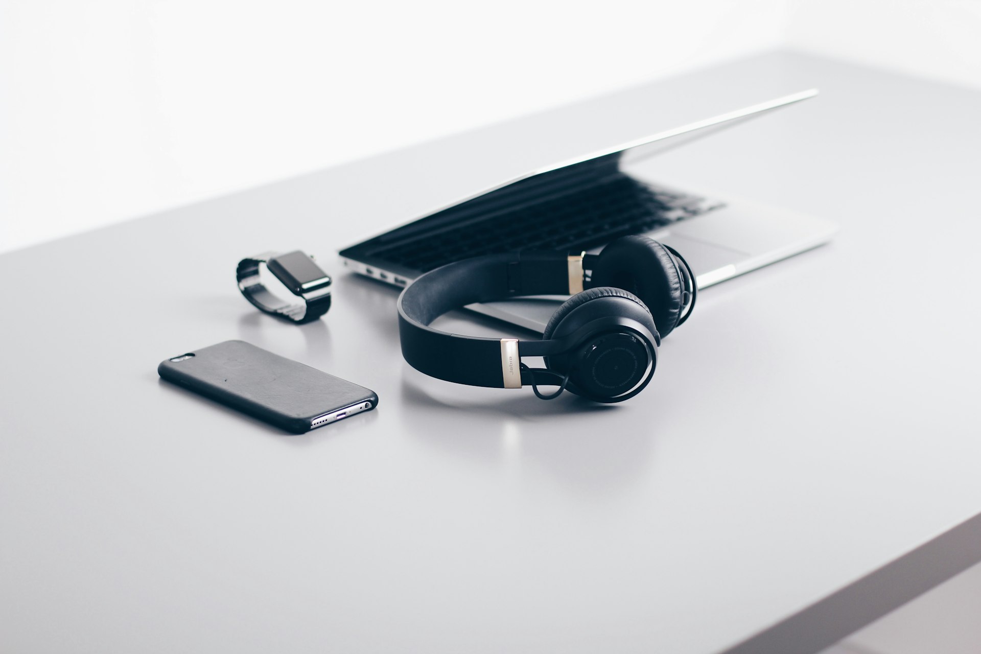 Minimalist workspace with laptop, headphones, smartphone and smartwatch