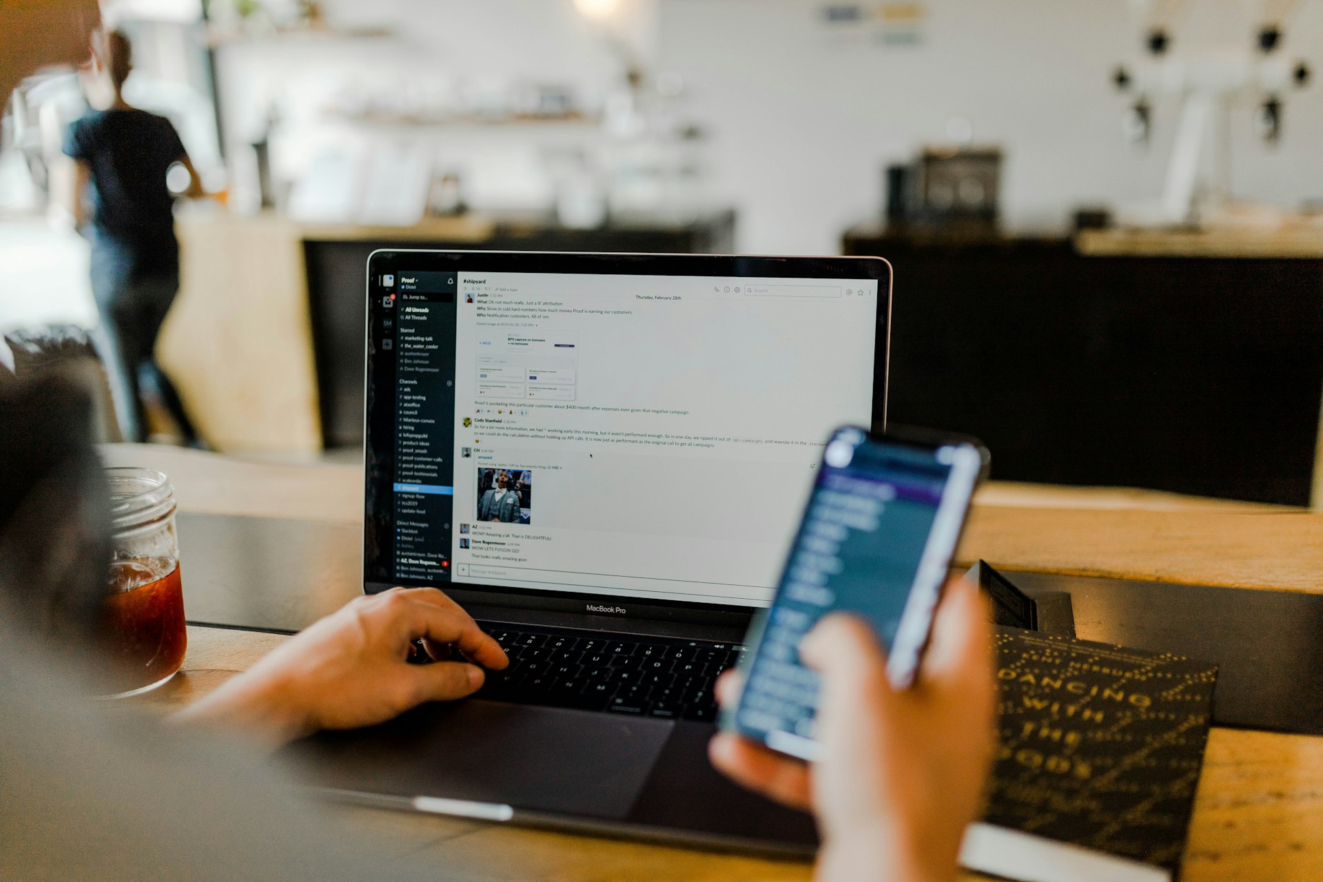 Person working on laptop and phone at workspace