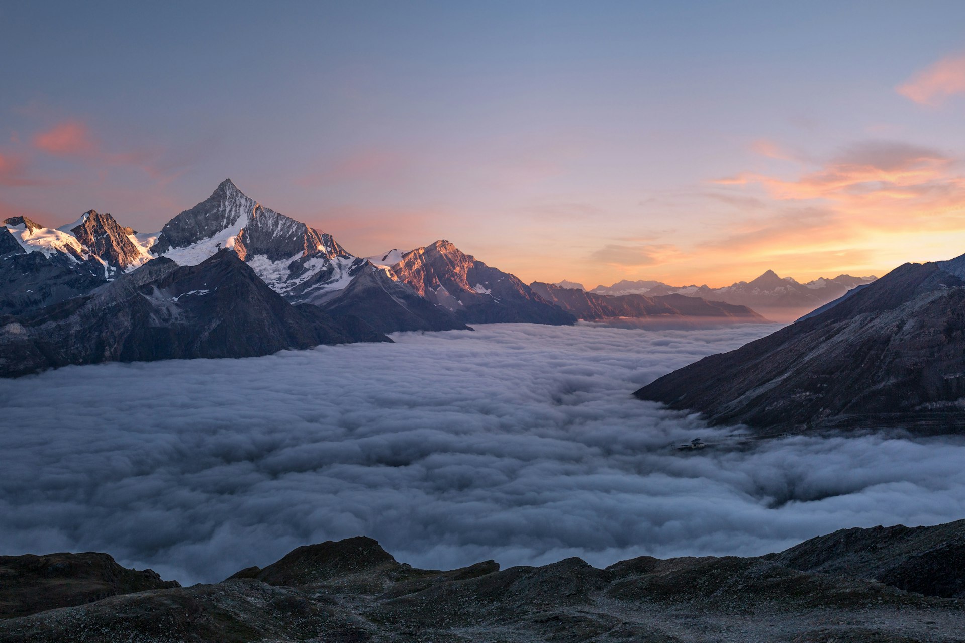 Mountain peaks above clouds at sunset showing remote landscape