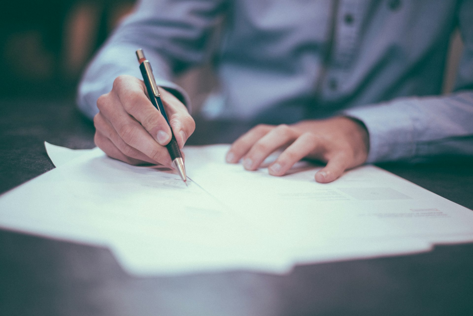 Person signing a contract document with a pen